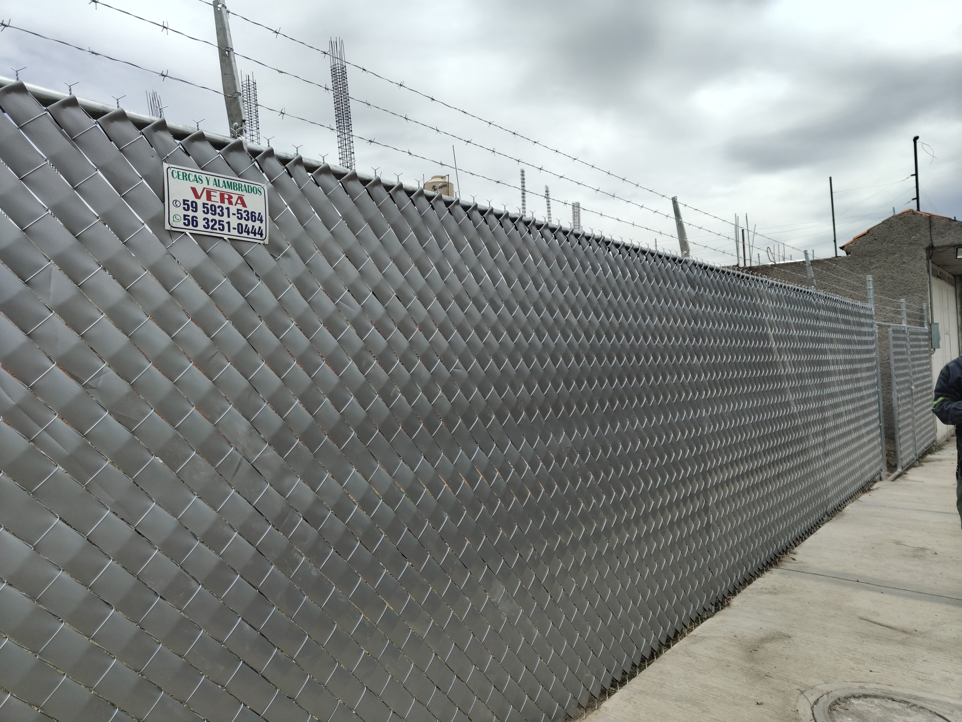 Instalación profesional de malla concertina con follajes en muro existente